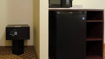 A compact kitchen with a microwave, refrigerator, and a small coffee machine.