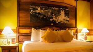 A hotel room with a large bed, two bedside tables with lamps, a wooden headboard, and a framed picture on the wall. - Nuestras Raices - Hotel Museo Restaurante (San Cristóbal de las Casas)