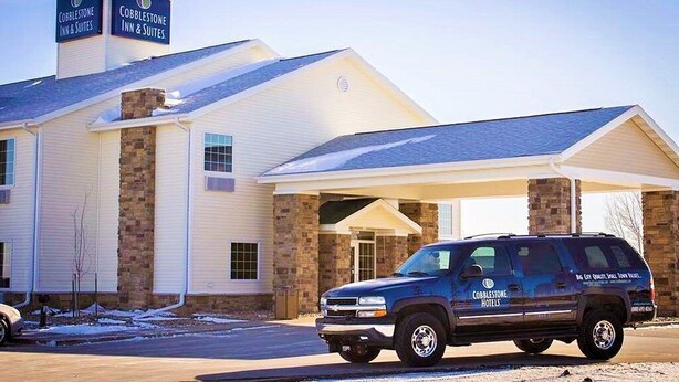 A Cobblestone Inn & Suites building with a stone facade and a covered parking area.