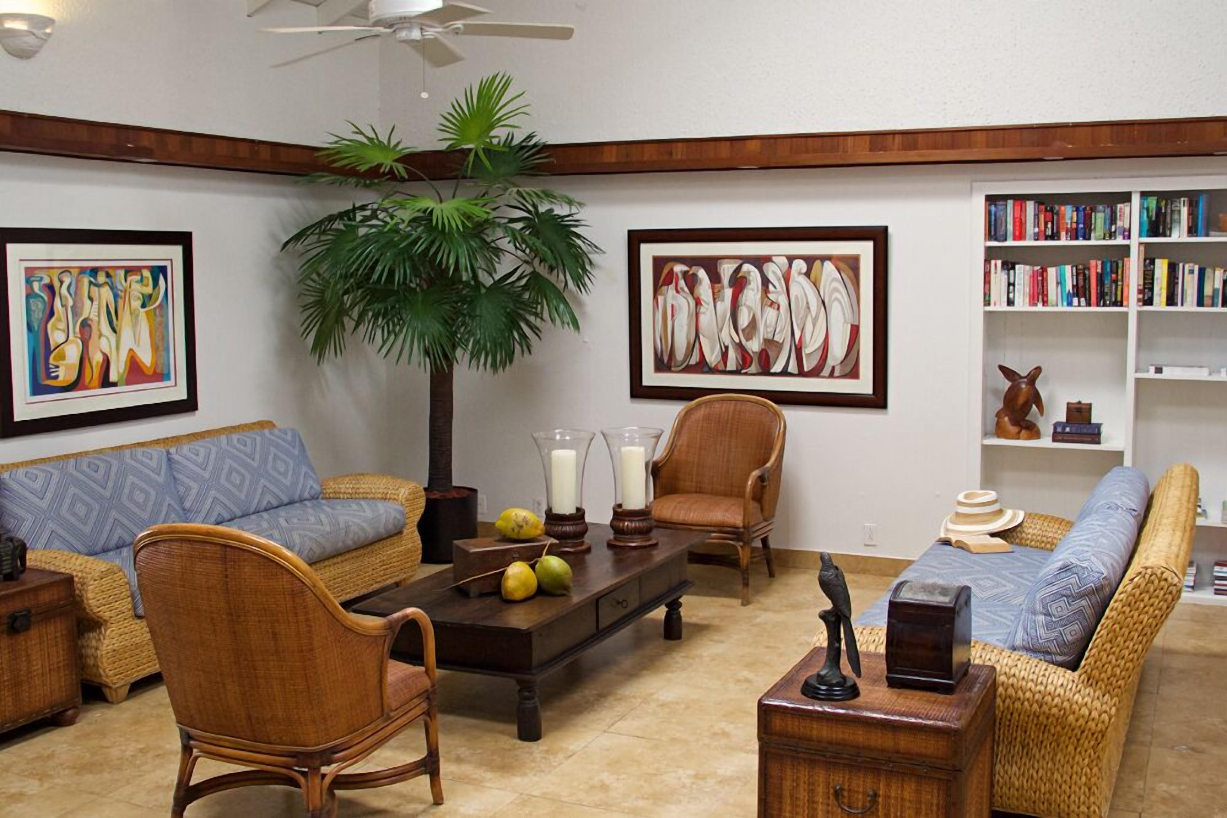 Uma sala de estar com sofá, poltronas, mesa de centro e estante de livros.