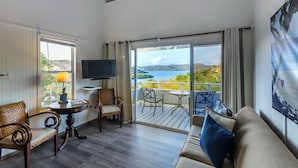 A spacious living room with a balcony, a television, and a view of the sea.