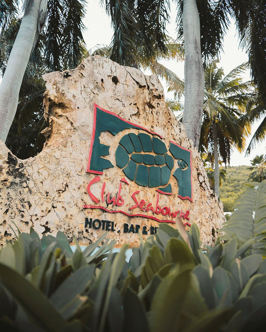 Un letrero con un gráfico de puño y el texto "Club Seabourn Hotel, Bar & Restaurant" sobre un fondo rugoso y con textura.