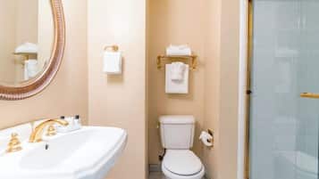 A bathroom with a white sink, gold fixtures, a toilet, and a shower with a glass door.