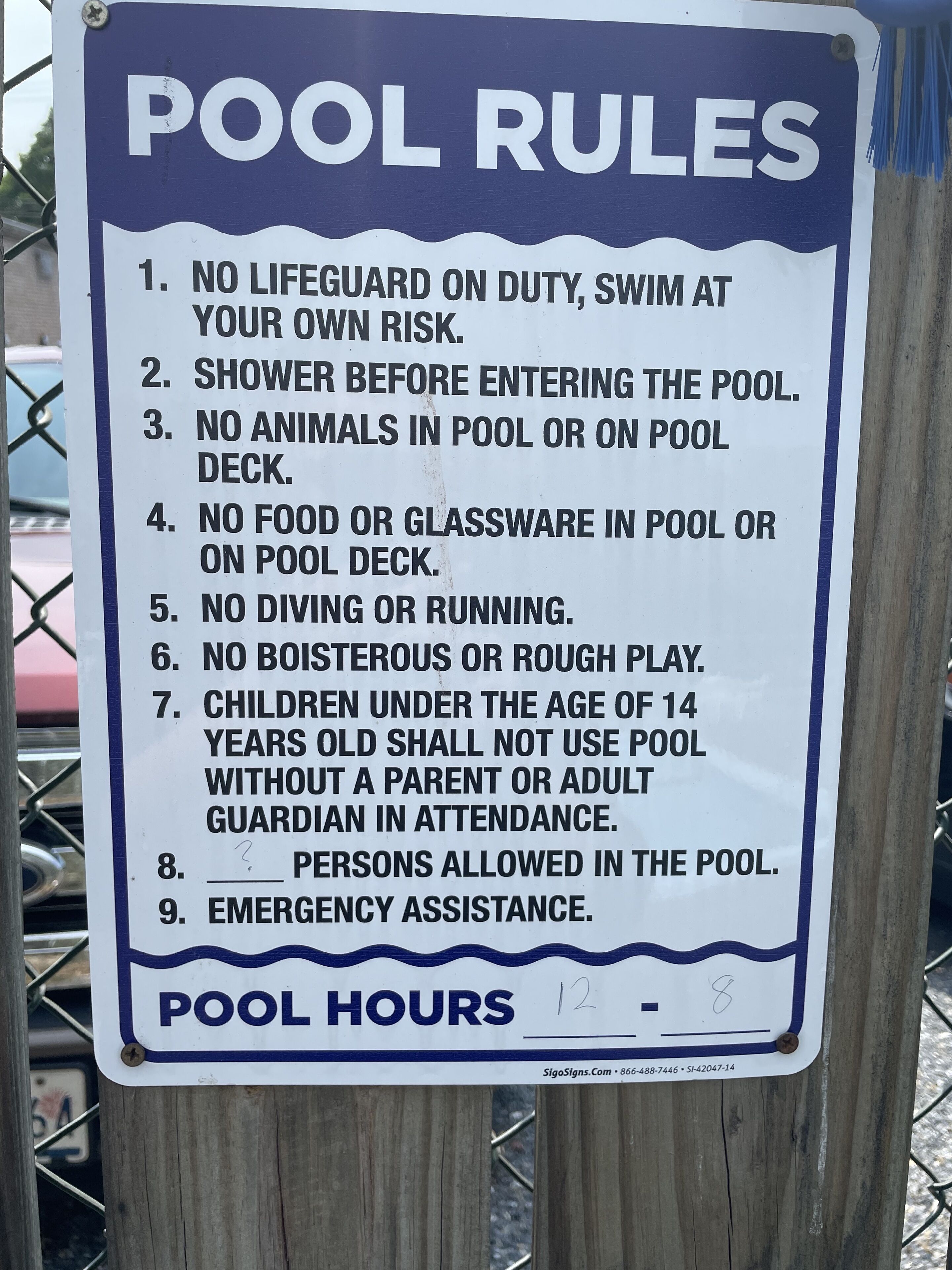 Un panneau indiquant les règles d’utilisation de la piscine et ses horaires d’ouverture.