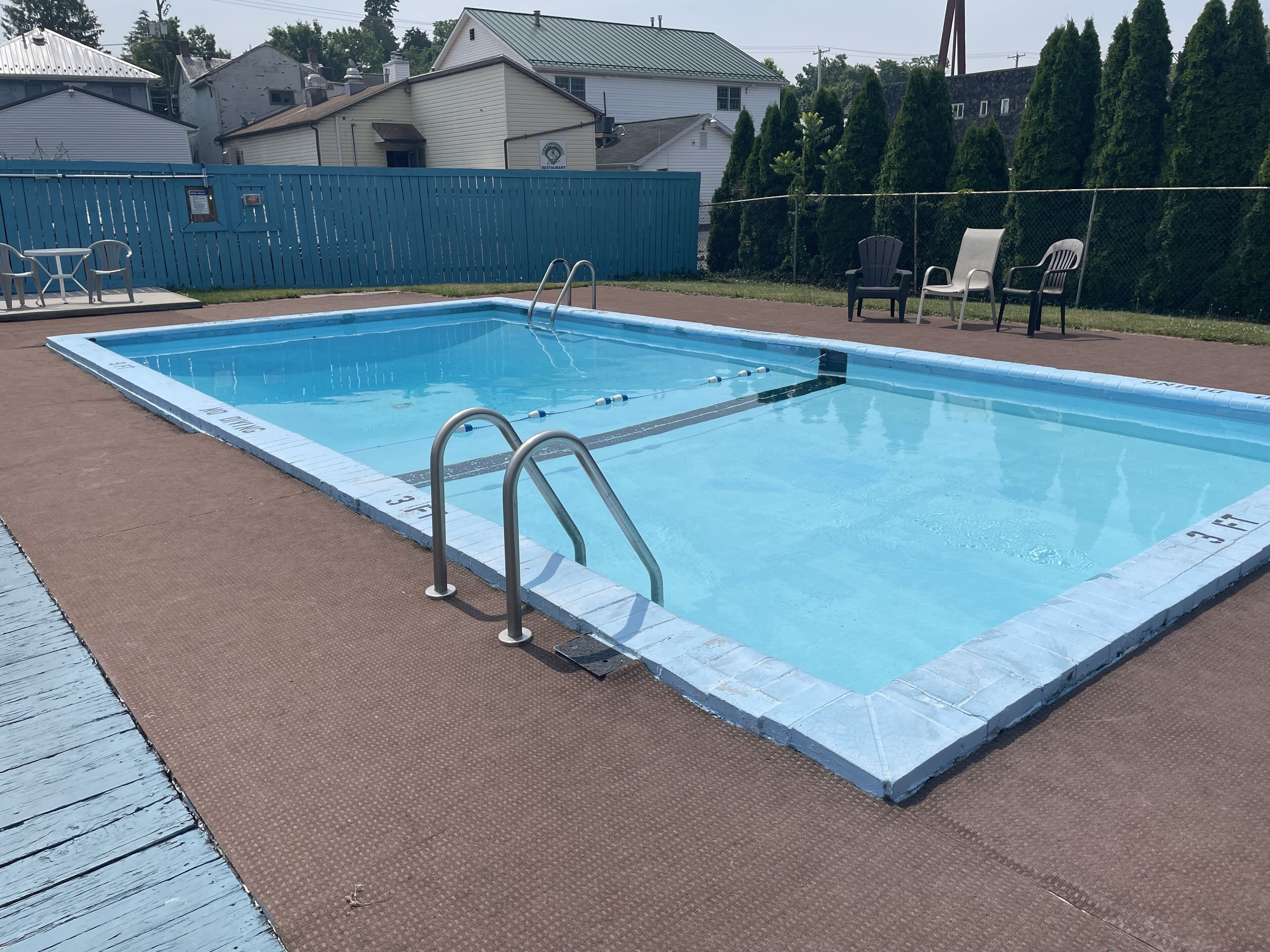 A rectangular swimming pool with a blue border and two ladders on one side.