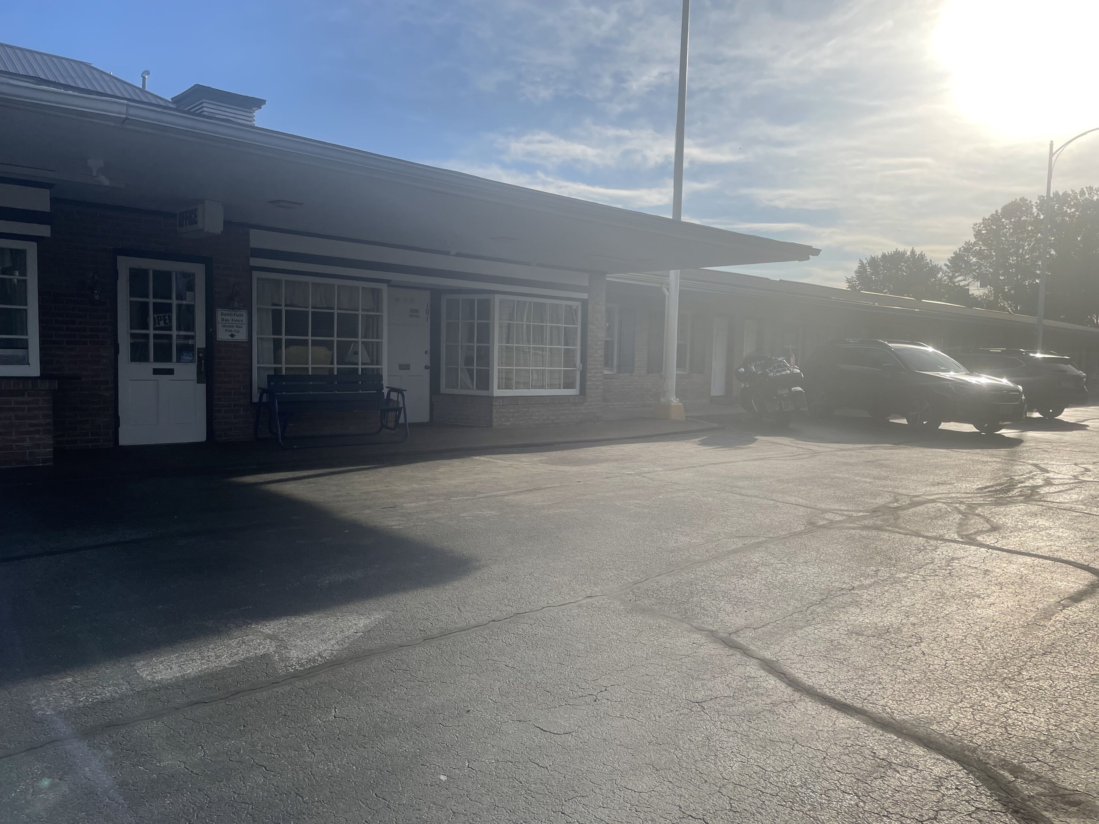 A building with a brick facade, a covered entrance, and a parking area with cars.