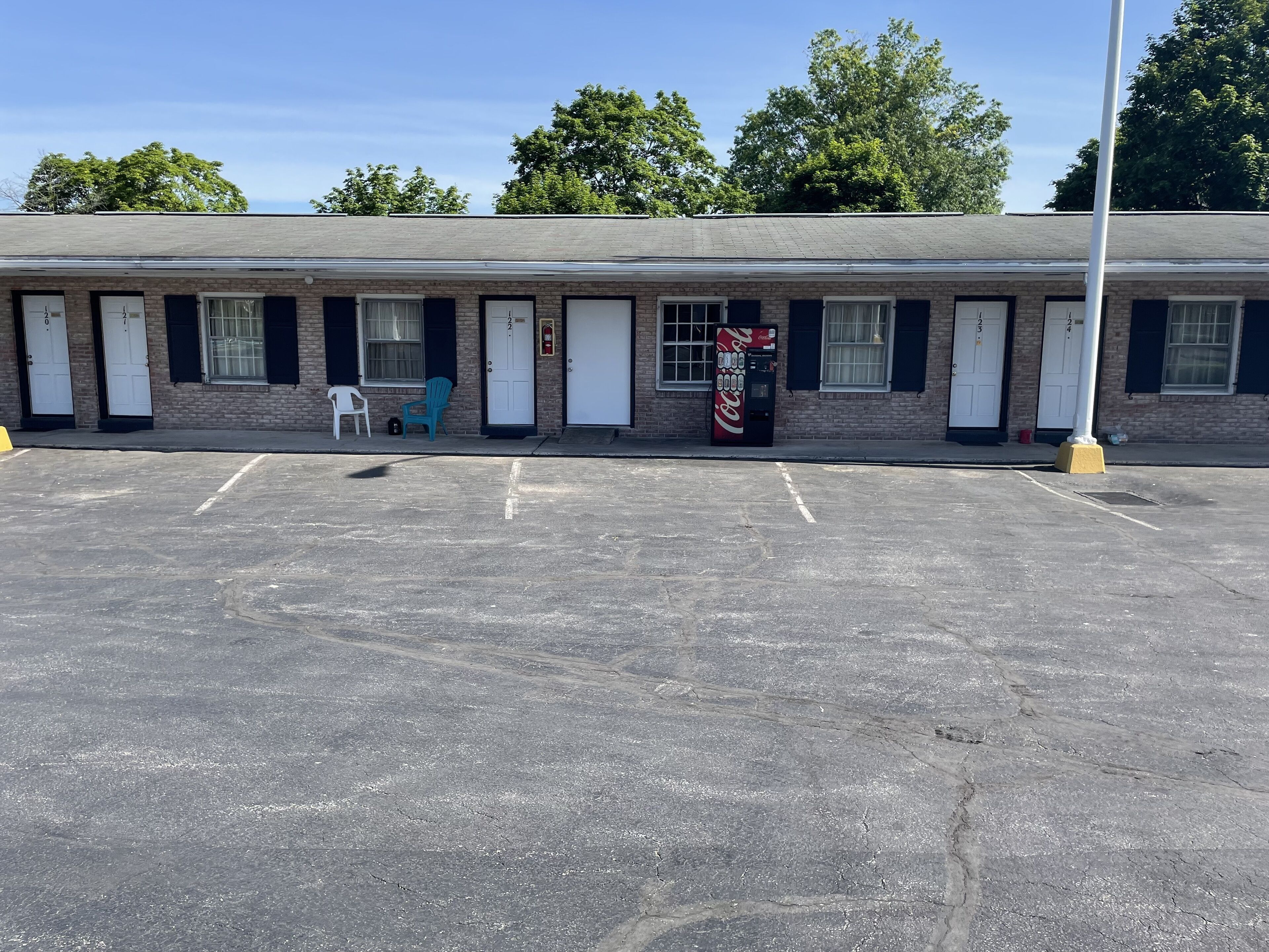 Ein Motel mit einer Reihe von einstöckigen Zimmern, einer Coca-Cola-Getränkeautomaten und einem Parkplatz.