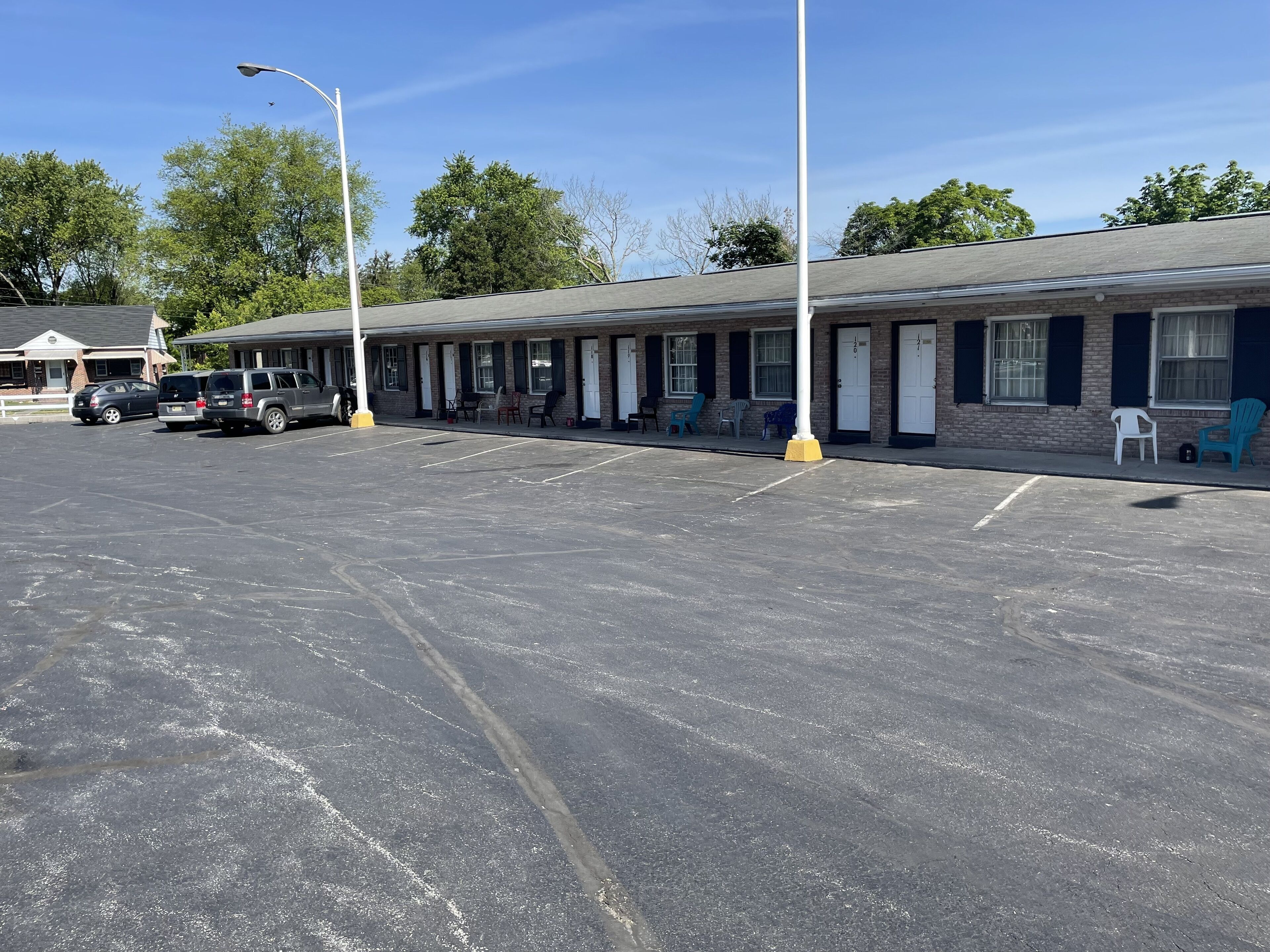 A motel with a row of rooms, a parking lot, and a few parked cars.