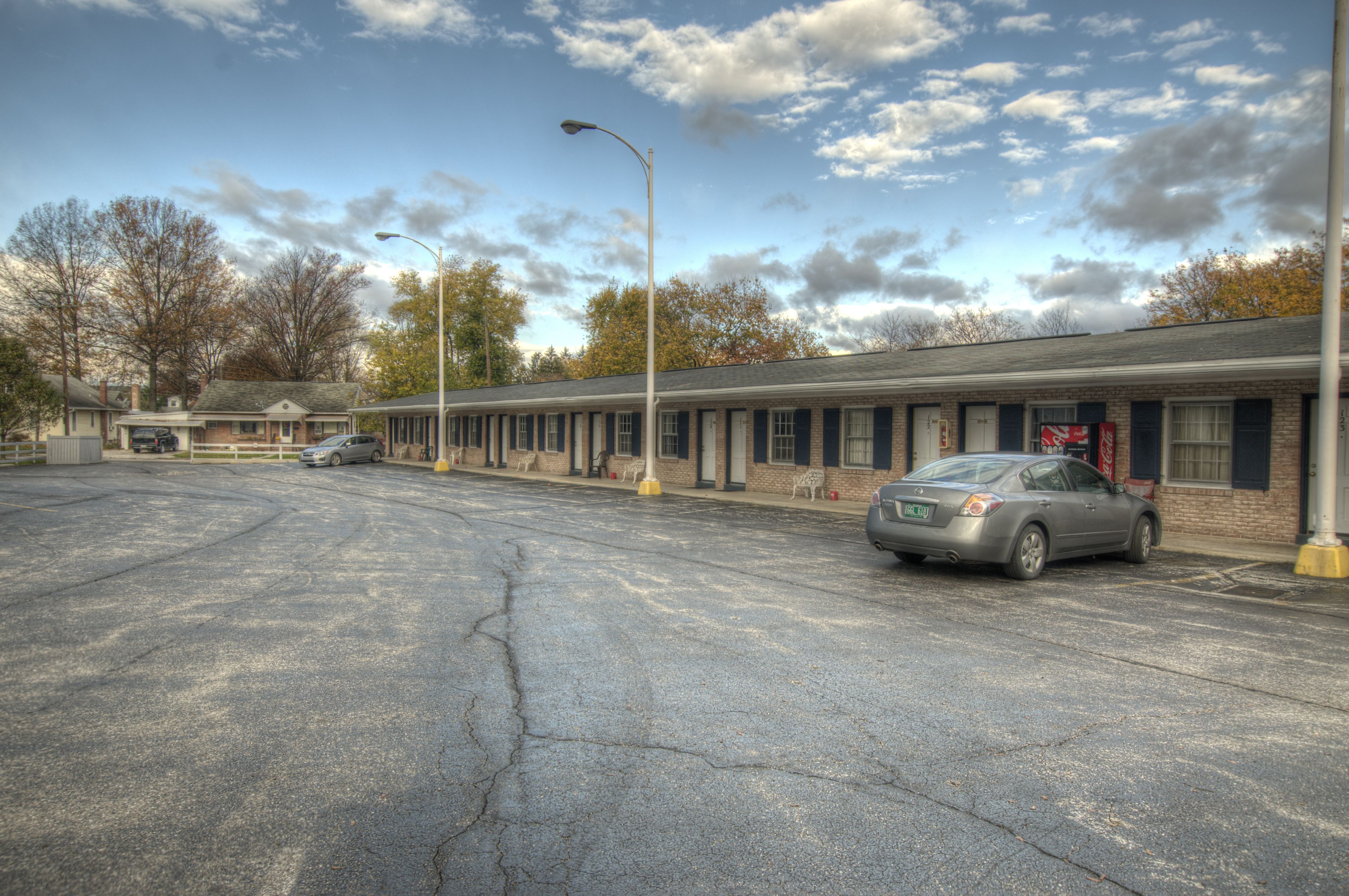 A motel with a parking lot, a single-story building, and a row of rooms with a brick facade.