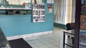 A reception area with a counter, informational posters, a bulletin board, and a seating area. - Colton Motel Gettysburg (Gettysburg)