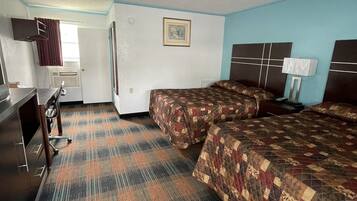 A hotel room with two beds, a desk, a chair, a TV, and a window with curtains.