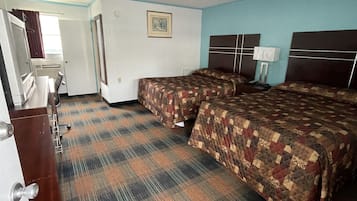 A hotel room with two beds, a desk with a chair, a dresser, and a window with curtains.