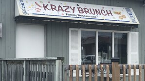 A restaurant named "Krazy Brunch" with a signboard, wooden fence, and a window. - Travellers Motel - New Wing (Owen Sound)