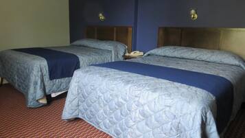 Two single beds with blue headboards and footboards, a red carpet, and a wall-mounted telephone.