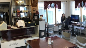 A restaurant with wooden beams, a chandelier, and a TV. - Travellers Motel - New Wing (Owen Sound)