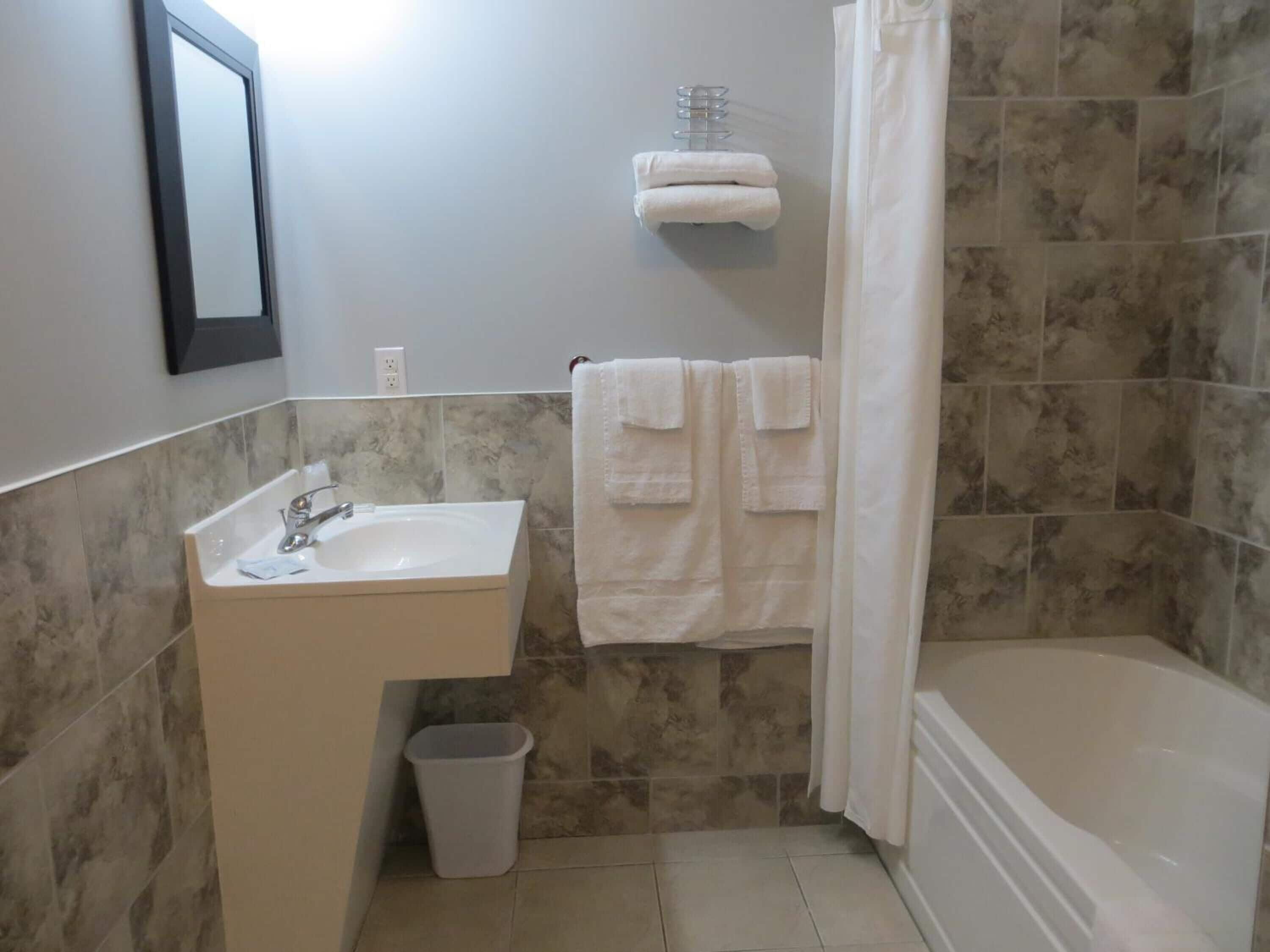 Un baño con lavabo, espejo, toallero y cortina de ducha.