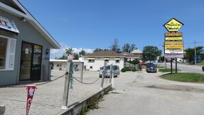 A motel with a sign advertising the lowest rates in town, air conditioning, and a T.M. variety store restaurant. - Travellers Motel - New Wing (Owen Sound)