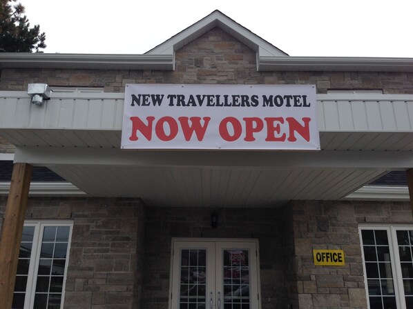Señal del motel New Travellers con un cartel de 'Abierto ya'.