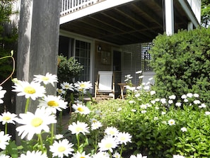 A porch with a wooden railing, a white chair, and a wooden table.