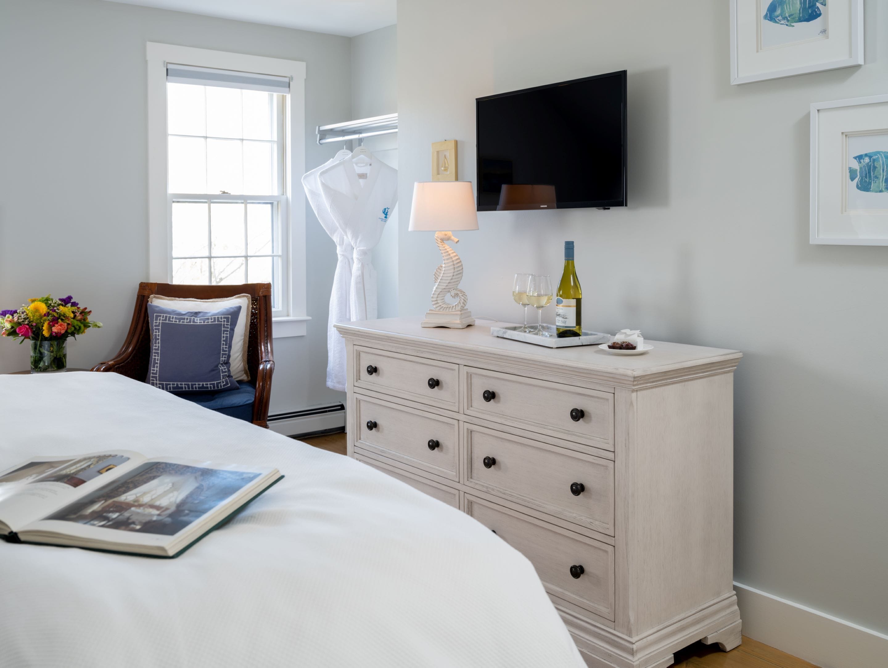 A bedroom with a bed, a dresser, a TV, and a window.