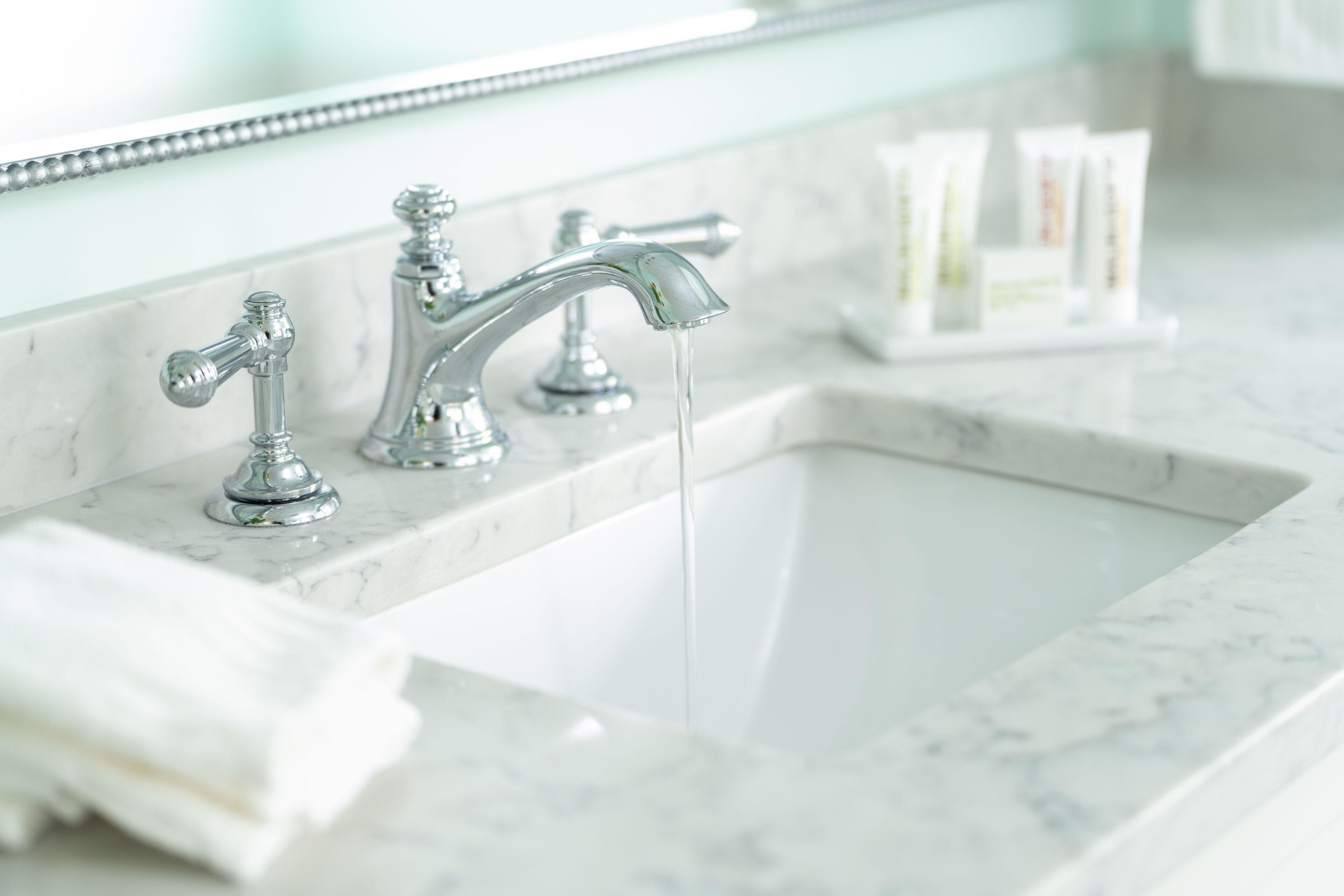 Une salle de bain avec un lavabo en marbre, deux robinets et un miroir au-dessus du lavabo.
