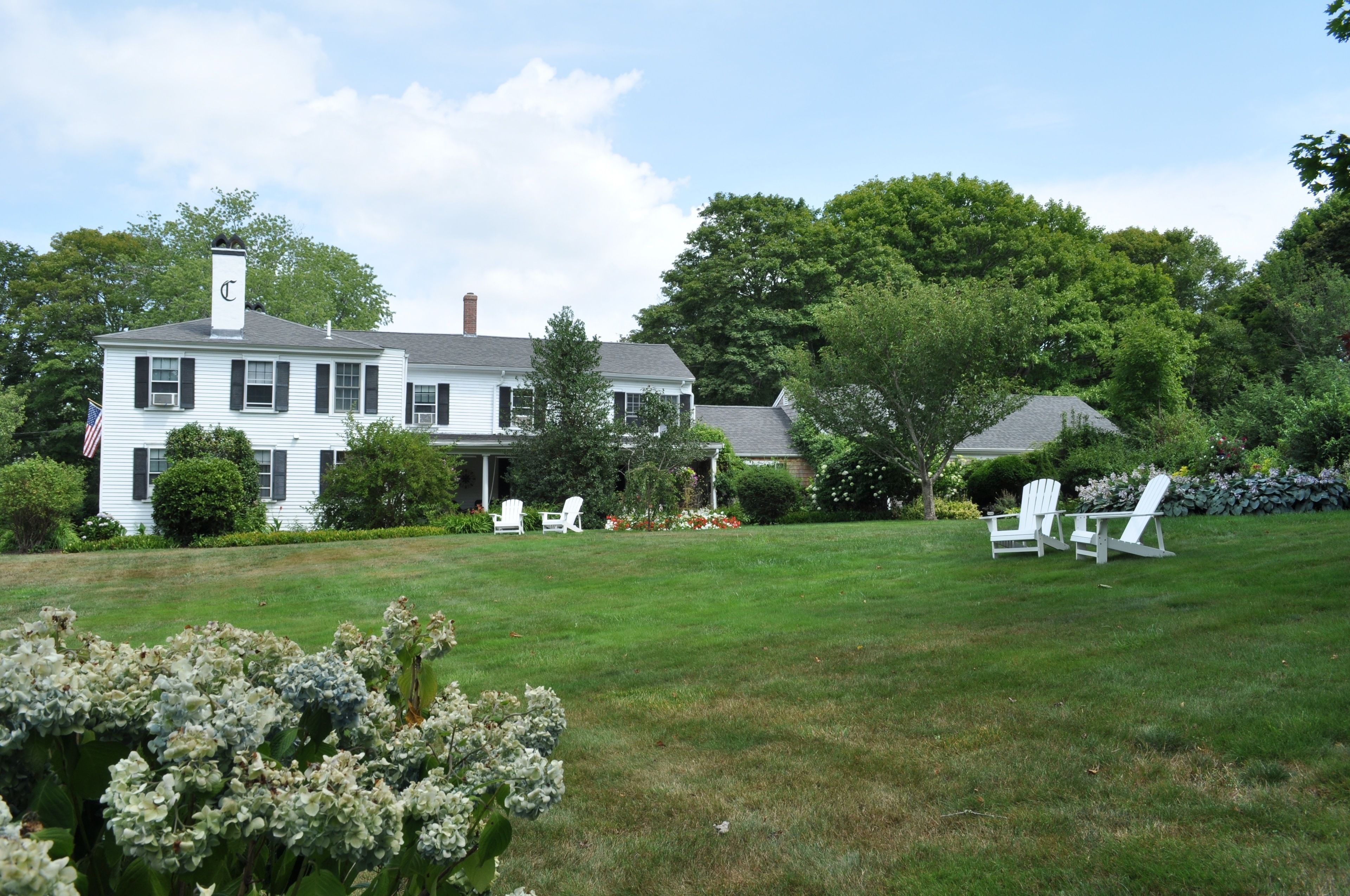 A large white house with a chimney, surrounded by a well-maintained lawn and trees.