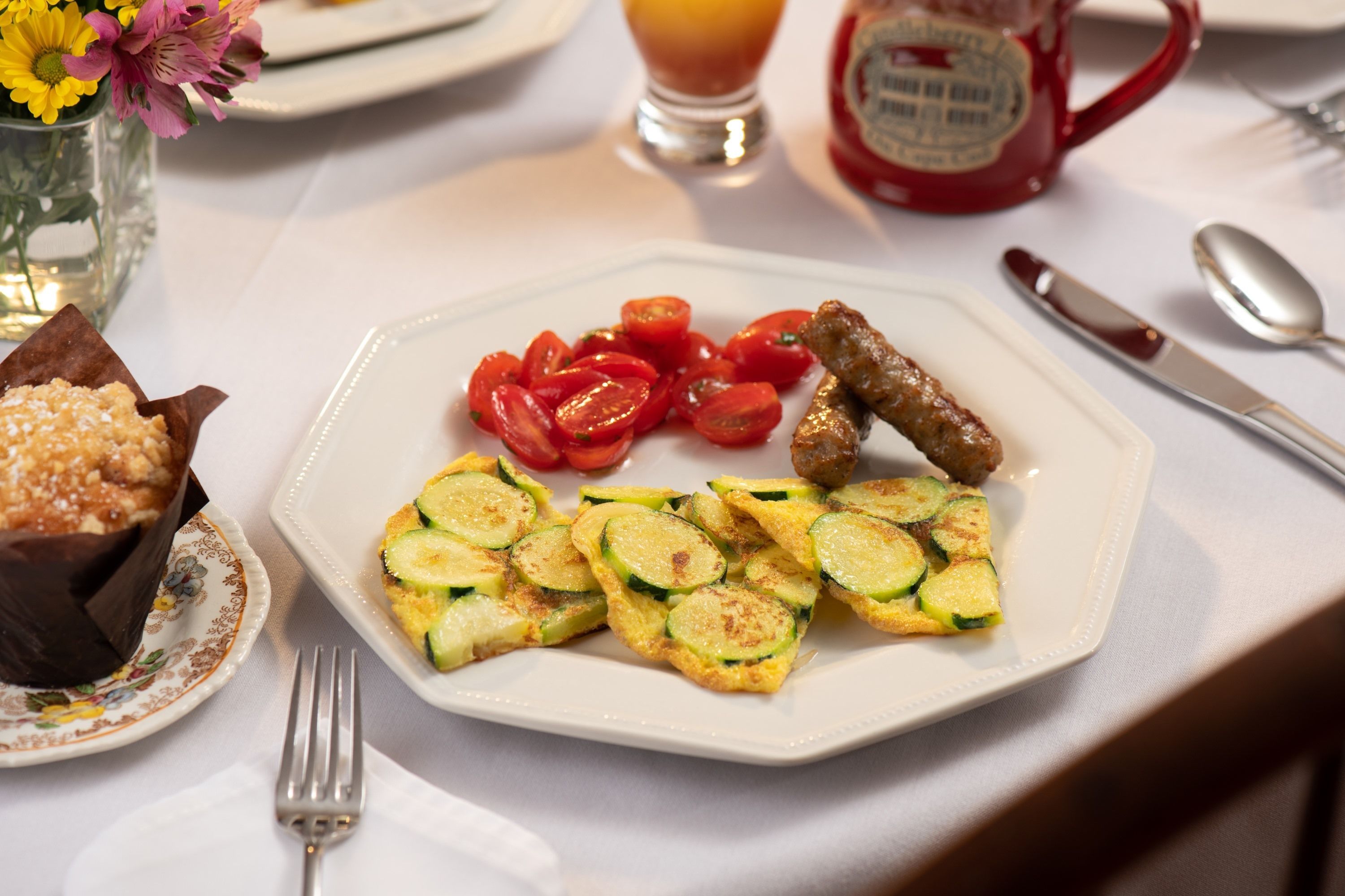 A plate with sliced zucchini, cherry tomatoes, and sausages.