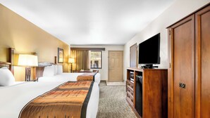 A hotel room with a large bed, a TV, a dresser, and a door. - Best Western Grande River Inn & Suites (Clifton)