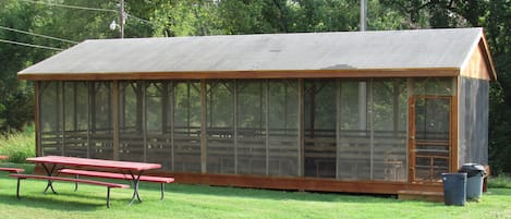 A small, single-story wooden structure with a covered porch and a large windowed section.