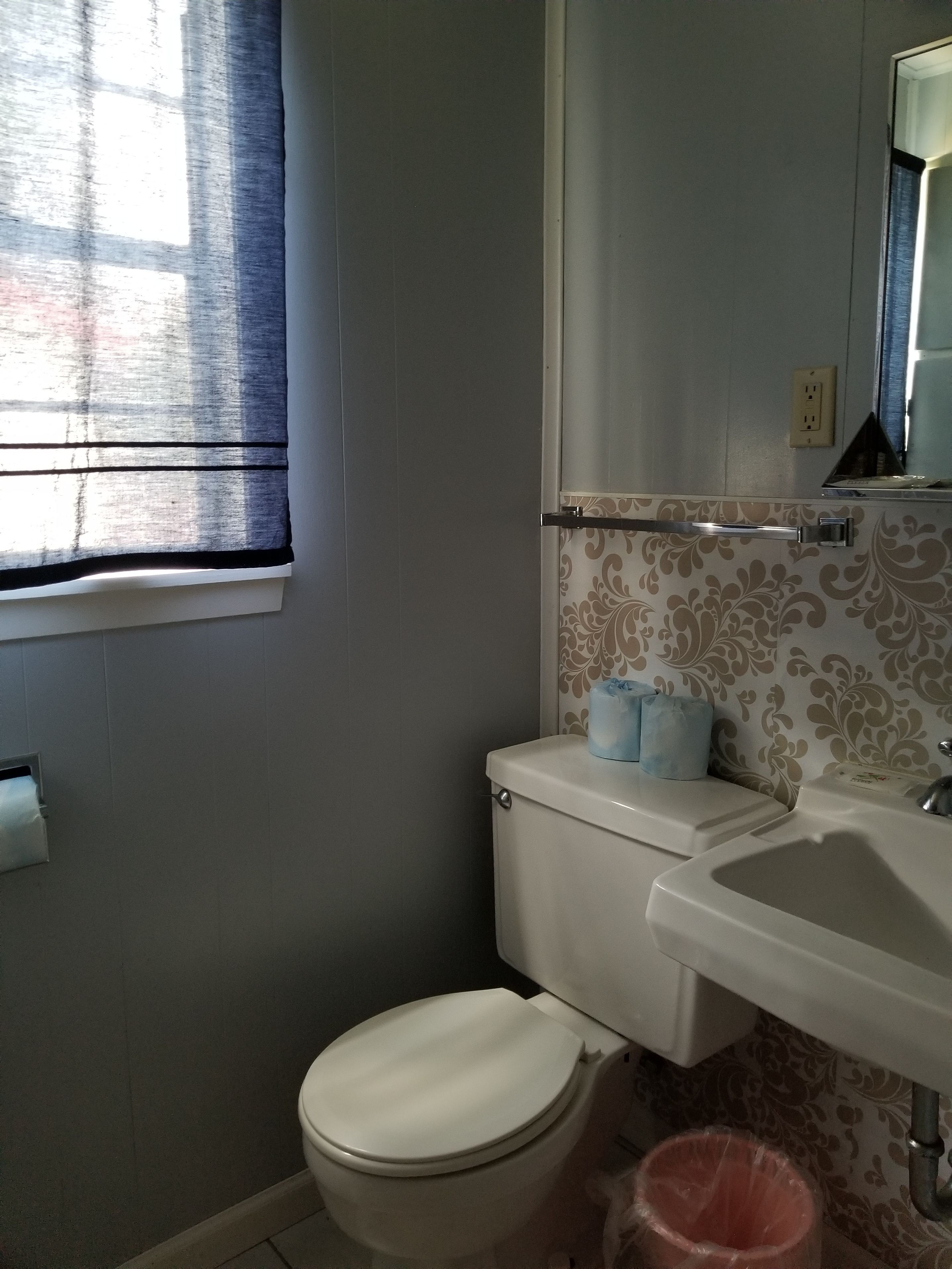 Un baño con inodoro, lavabo y ventana con persianas.