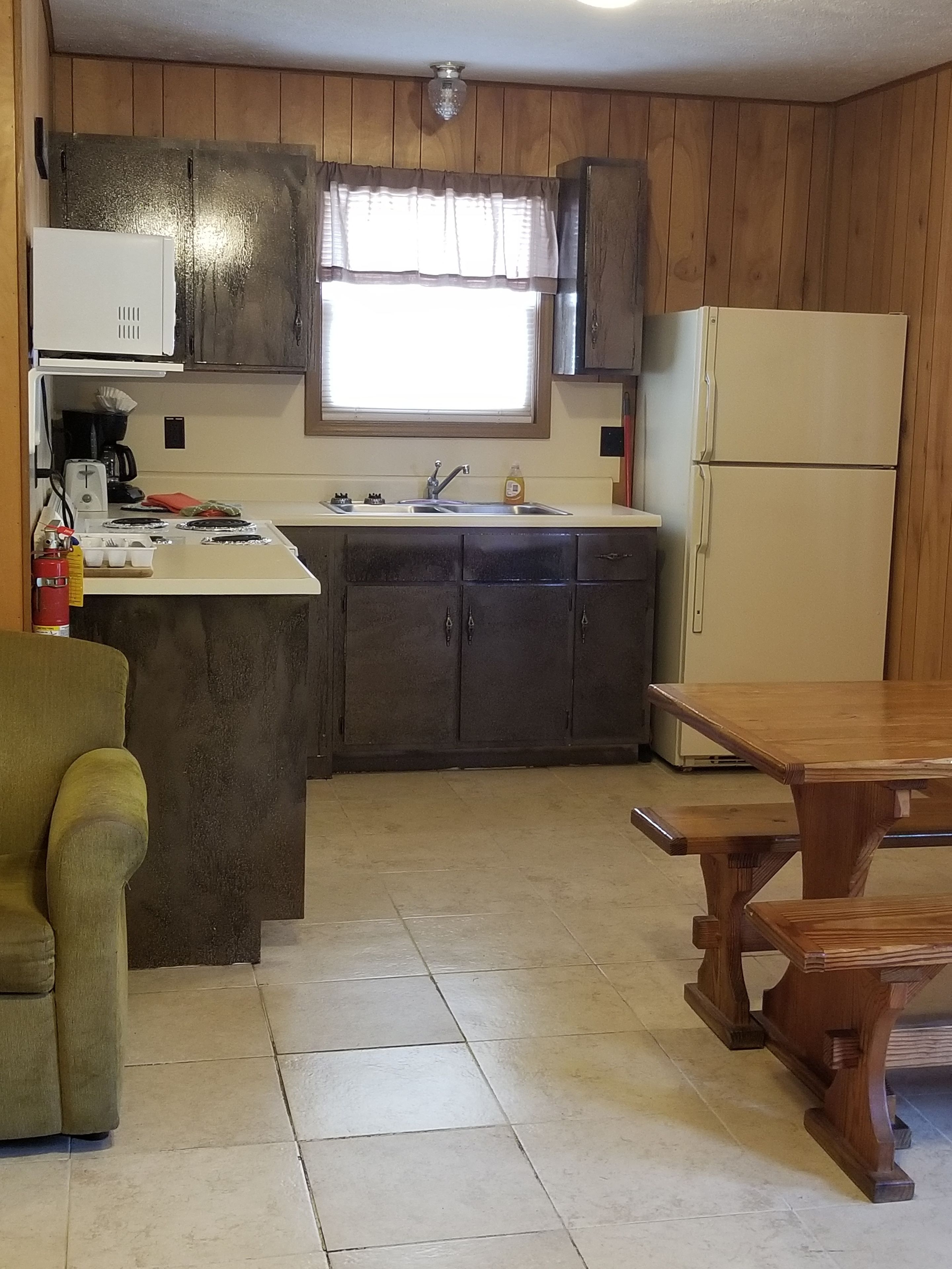 A compact kitchen with wooden cabinets, a sink, a stove, and a refrigerator.