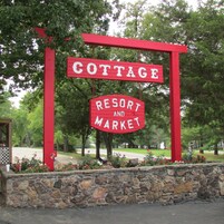 Un letrero rojo con letras blancas que dice 'COTTAGE RESORT AND MARKET'.