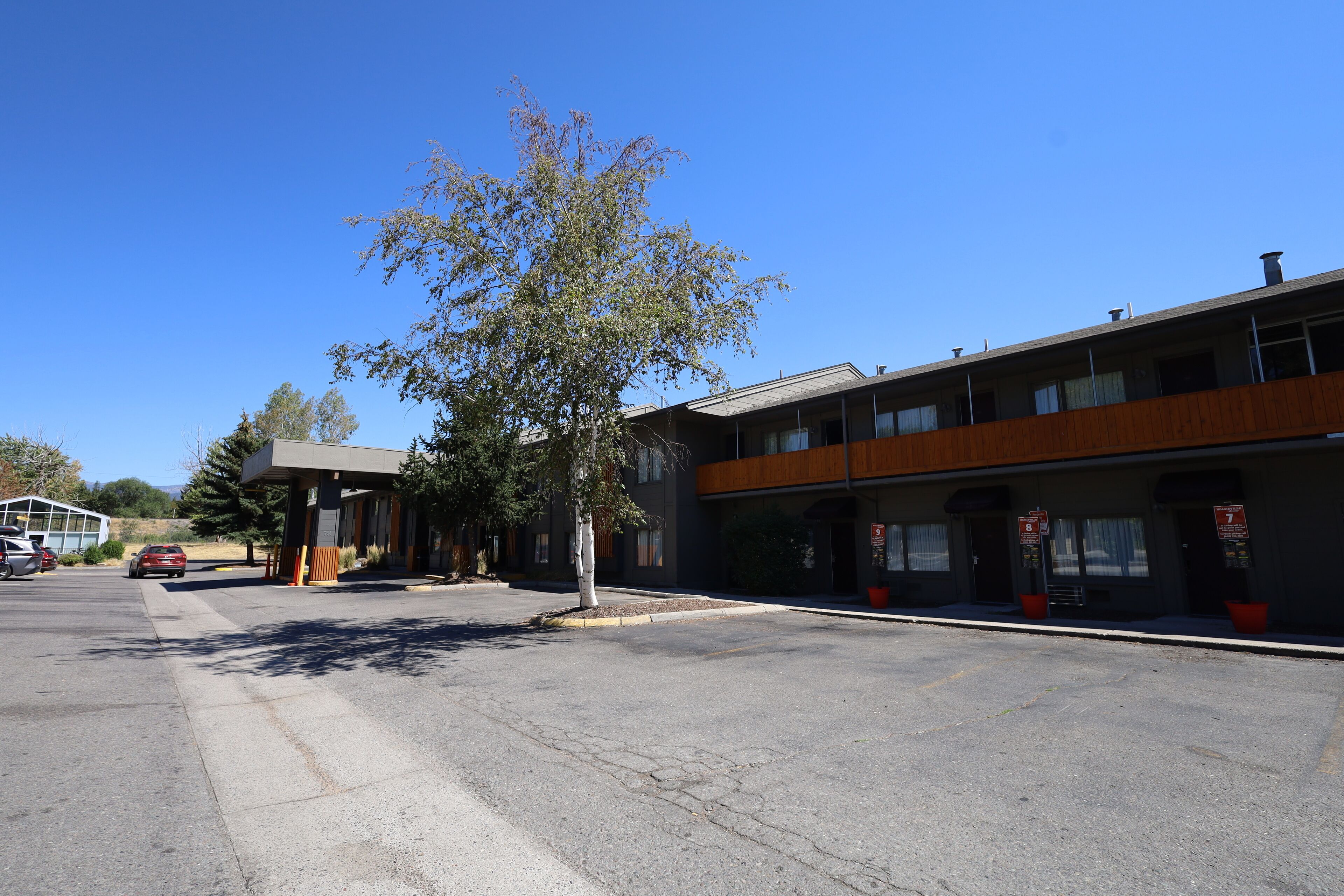 A building with a flat roof, large windows, and a parking lot.