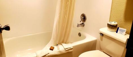 A bathroom with a bathtub, toilet, and a shower curtain.