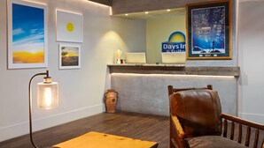 A reception area with a wooden reception desk, a leather chair, framed artwork, and a poster on the wall.