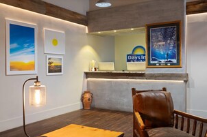 A hotel lobby with a reception desk, framed artwork, a leather chair, and a vase.