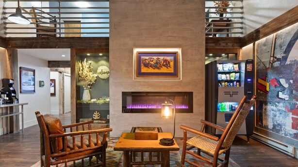 A lobby with a fireplace, wooden furniture, and a vending machine.