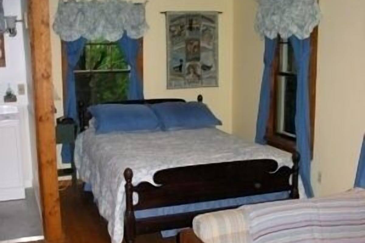 A bedroom with a wooden bed, a smaller bed, and a nightstand.