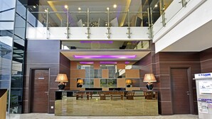 A modern hotel lobby with a reception desk, seating area, and a glass railing overlooking the lower level. - Serela Waringin (Bandung)
