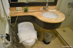 A bathroom with a toilet, sink, and a trash can. - View Park Hotel (Tagaytay)