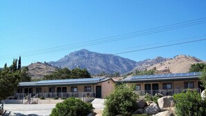 A motel with two-story buildings, solar panels on the roofs, and a mountainous backdrop.