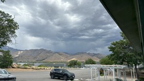 A parking area with a green car and a white car, a covered seating area, and mountains in the background. - Lakeshore Lodge (Wofford Heights)
