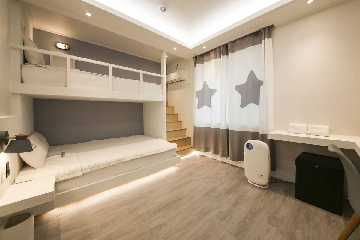 Une chambre moderne et bien éclairée, équipée d’un lit superposé, d’un bureau et d’une chaise.