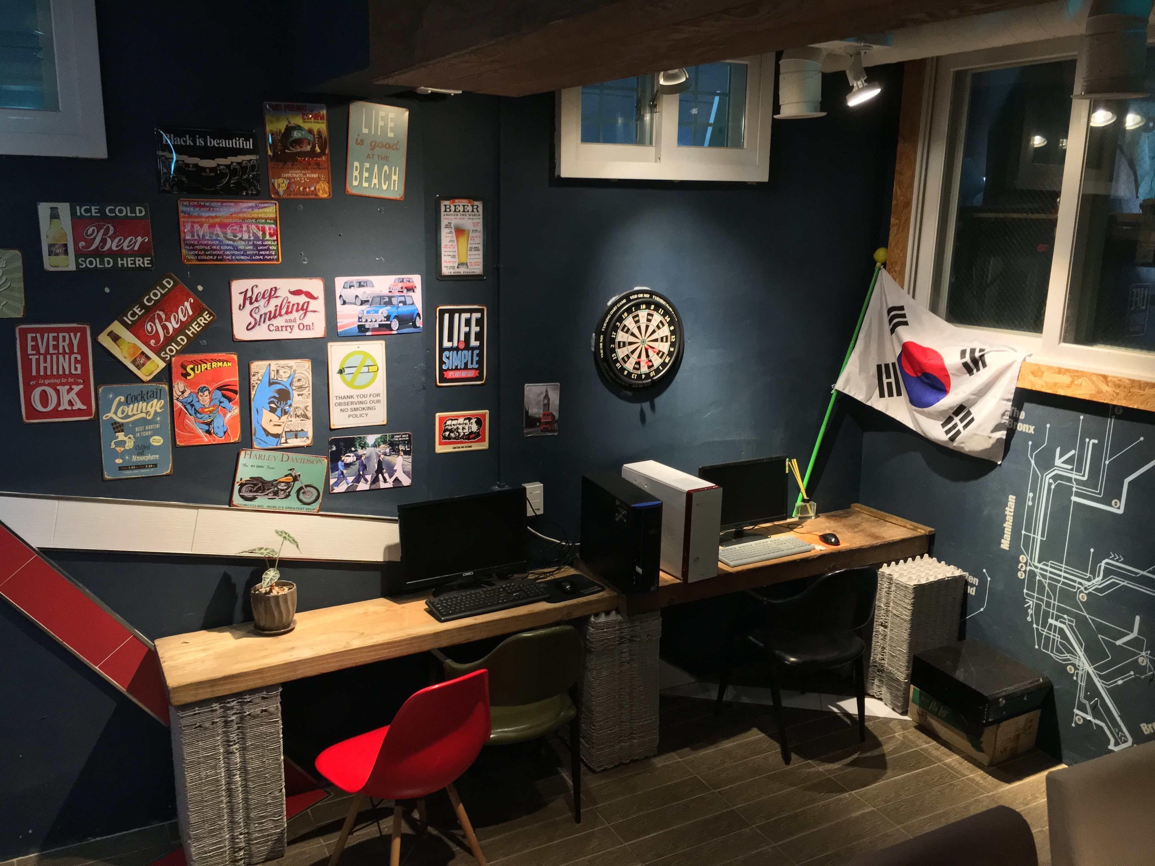A room with a desk, computer, and various posters on the wall.
