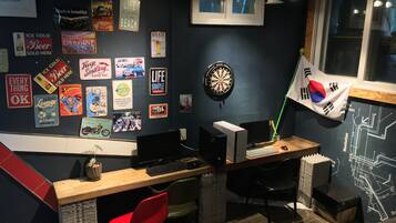 A room with a desk, computer, and various posters on the wall.