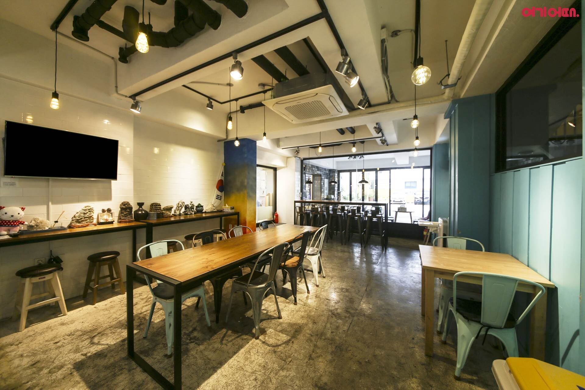 A spacious café with high ceilings, exposed ductwork, and a variety of seating options including tables and chairs.