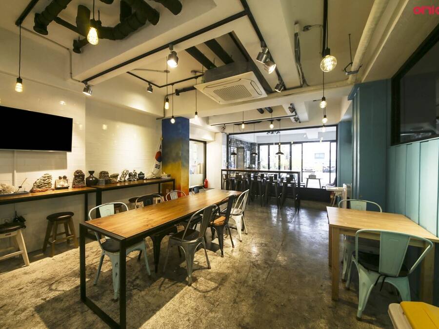 A spacious café with high ceilings, exposed ductwork, and a variety of seating options including tables and chairs.