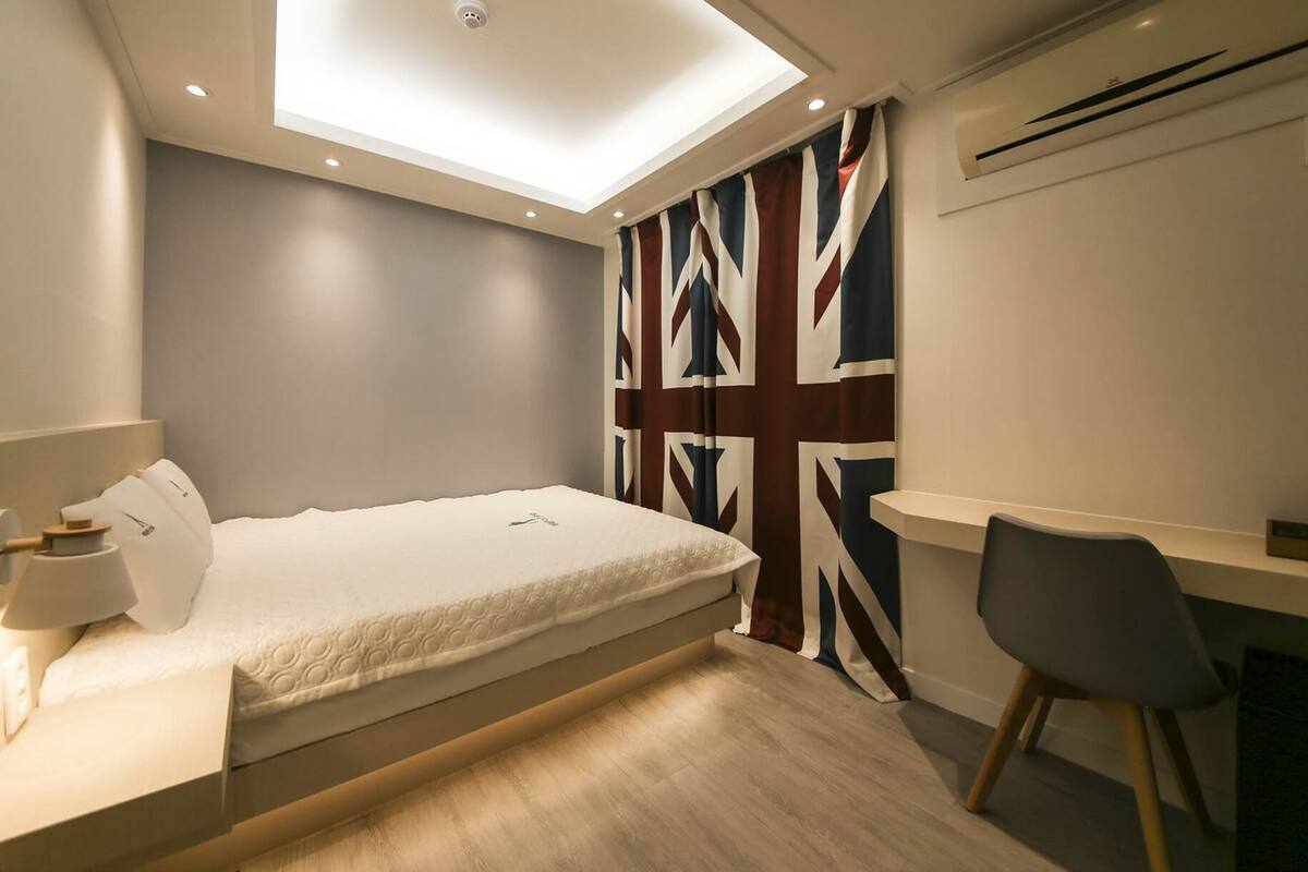 Une chambre à coucher moderne, comprenant un lit, une table de chevet, une lampe et un bureau avec une chaise.