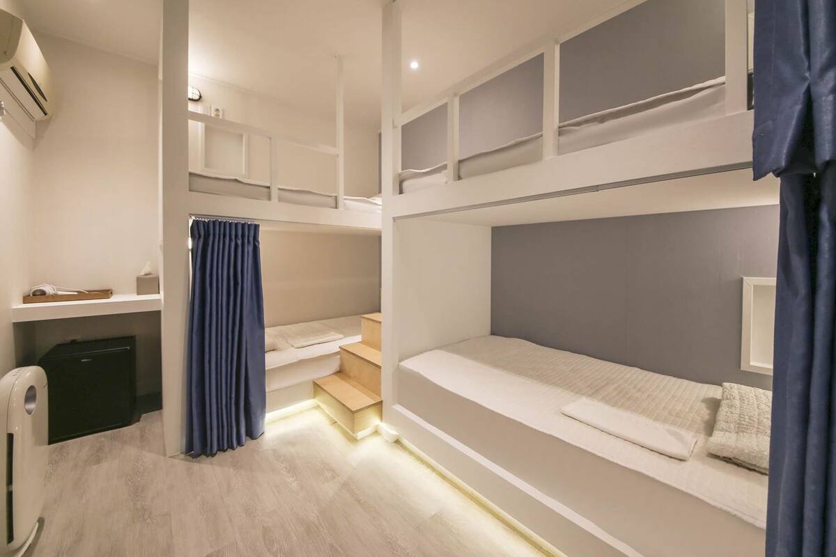 Une chambre avec un lit superposé, un bureau, une chaise et un petit meuble de rangement.