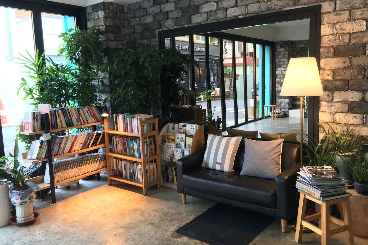 Un salon confortable avec un canapé en cuir noir, une bibliothèque et une lampe.